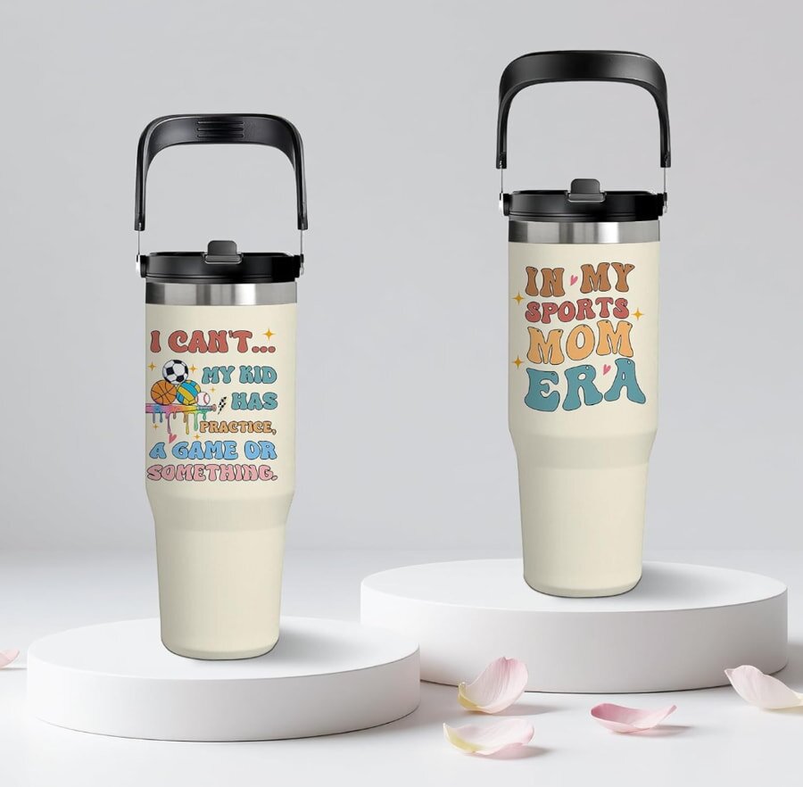 Two cream-colored tumblers with sports mom designs