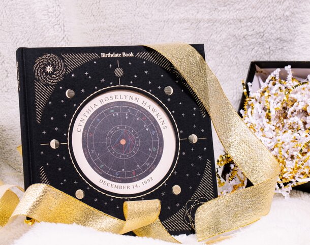 A black and gold clock adorned with a gold ribbon and a gold star, showcasing an elegant design.