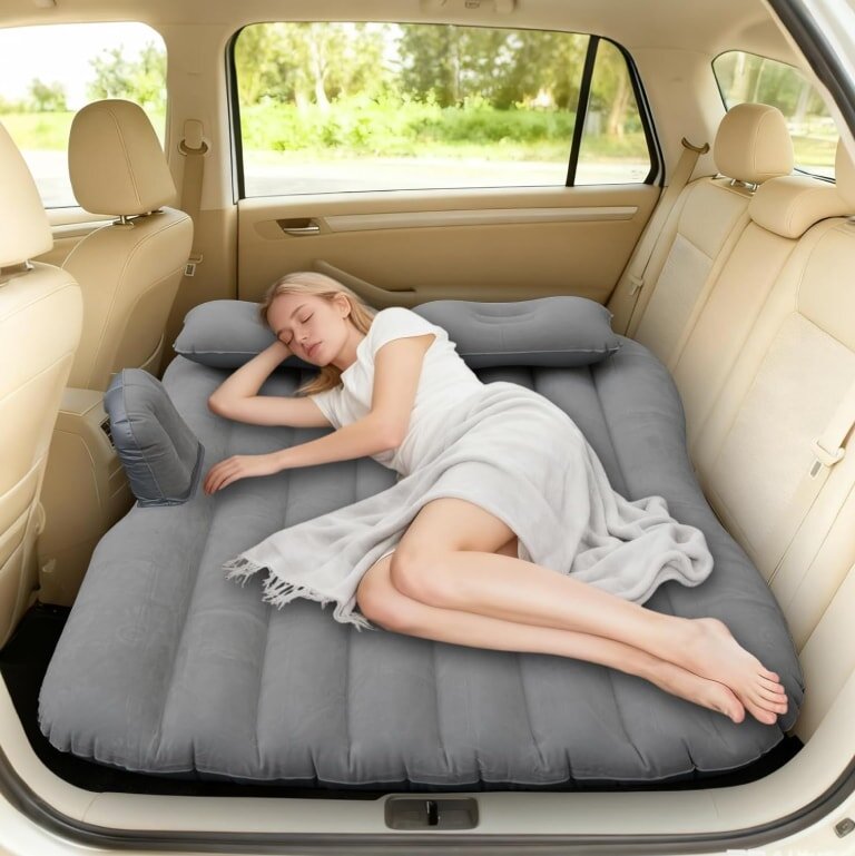 A woman rests on an air mattress in the back of a car, enjoying a moment of sleep.