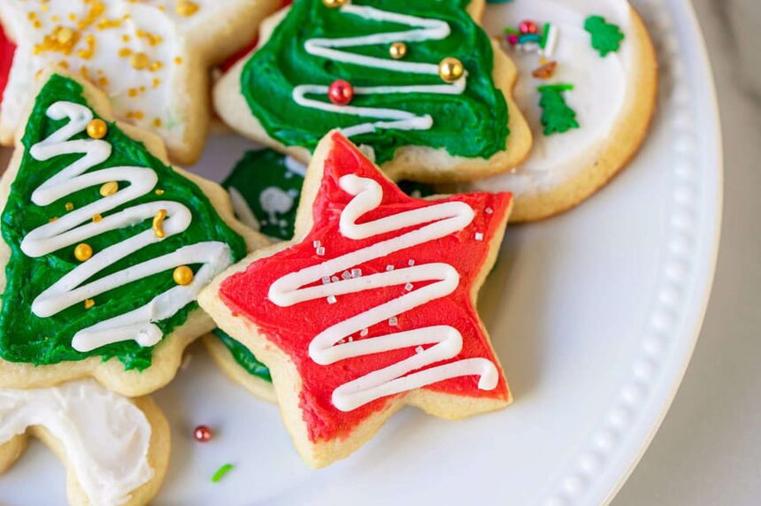 A white plate filled with decorated Christmas sugar cookies in various festive shapes and colors.