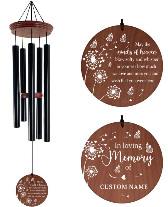 Wind chime with black metal tubes and a wooden disc featuring white dandelion and butterfly design. Text reads heartfelt memory message, conveying a peaceful, nostalgic tone.
