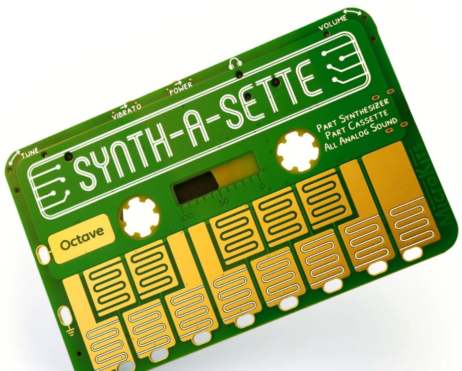 Green and gold cassette-shaped synthesizer with "Synth-a-Sette" text. Features include tuning, vibrato, power controls, and labeled octave and sound elements. Retro design.