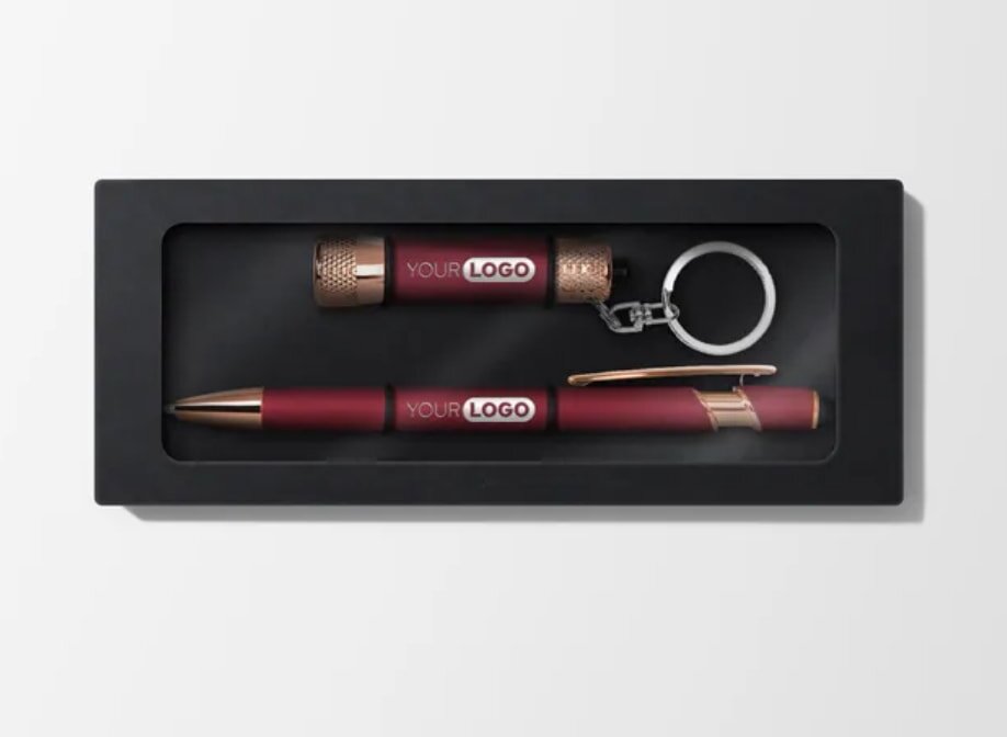 A black gift box containing a red pen and flashlight keychain with bronze accents and customizable "Your Logo" labels, set against a white background.