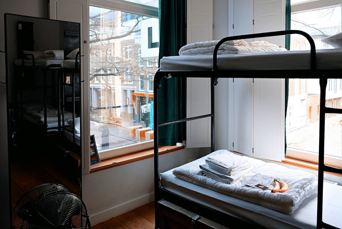 A room with two stacked bunk beds and a window, creating a bright and inviting atmosphere.