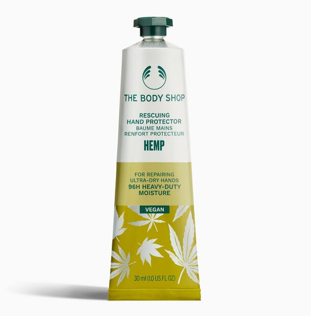 A tube of The Body Shop Hemp Hand Cream, featuring a green label and a natural hemp design, placed on a wooden surface.