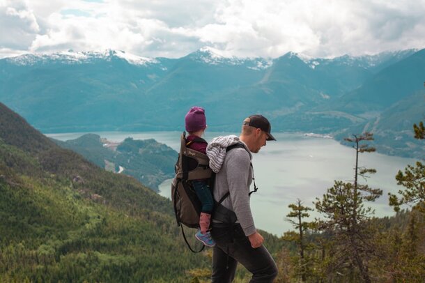 A man and a child hike together on a mountain top, enjoying the scenic view and fresh air.