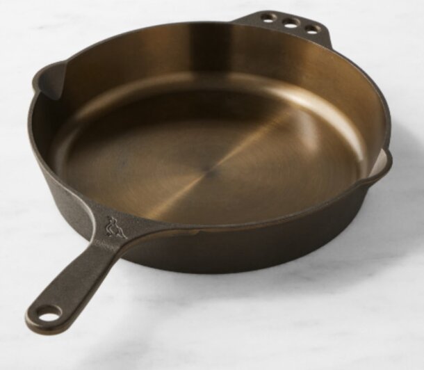 A cast iron skillet rests on a polished marble countertop, showcasing its dark finish against the light surface.