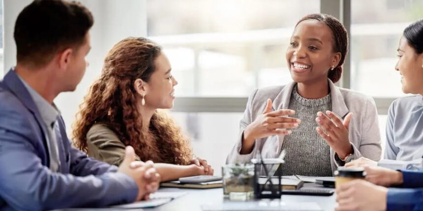 A group of business professionals engaged in discussion around a conference table.