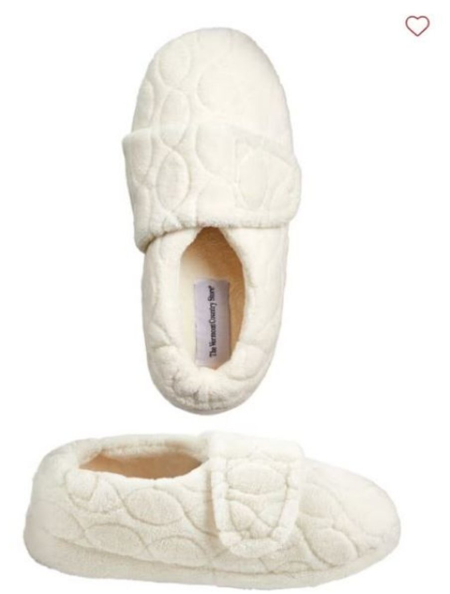 A pair of white slippers featuring a decorative bow on the side, designed for comfort and style.