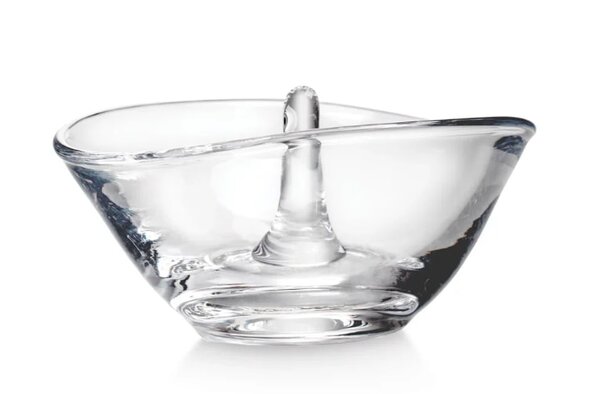 A glass bowl with a curved edge beside a small spoon, designed for serving or tasting food.