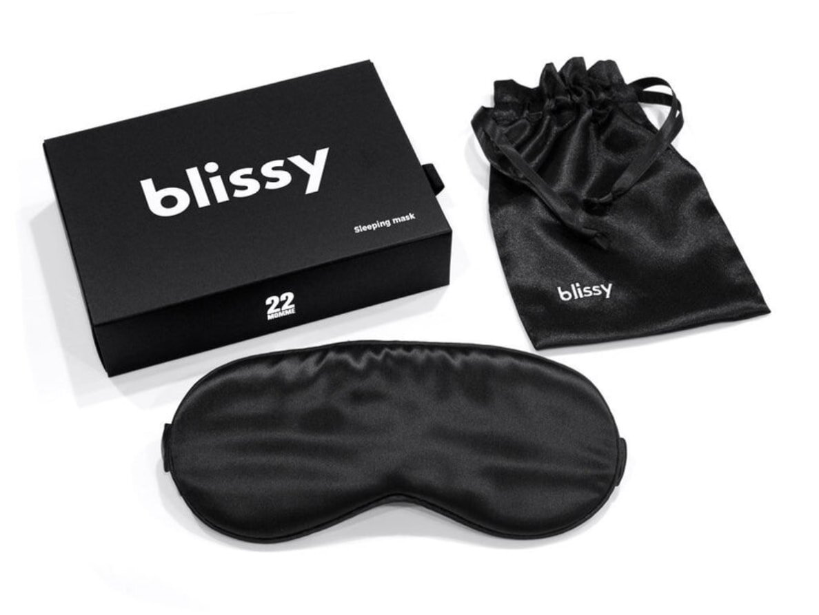 Blissy sleep mask displayed alongside a traditional sleep mask on a soft surface, highlighting their design and comfort features.