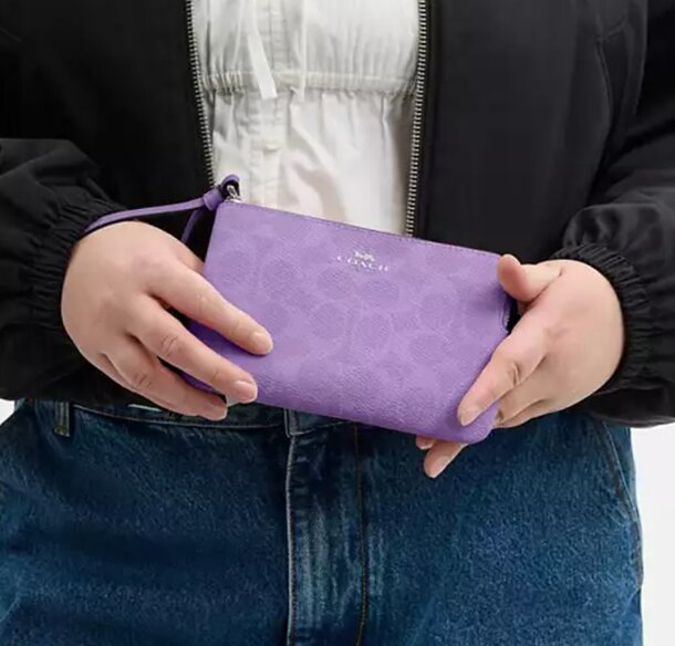 A woman holding a purple wallet, showcasing its vibrant color and stylish design.