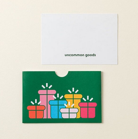 Gift card with "uncommon goods" text above a green sleeve featuring colorful, stylized gift boxes on a neutral background