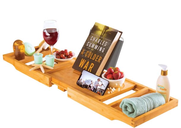 A wooden tray holds several books, a bottle of wine, and a glass of water, creating a cozy reading atmosphere.