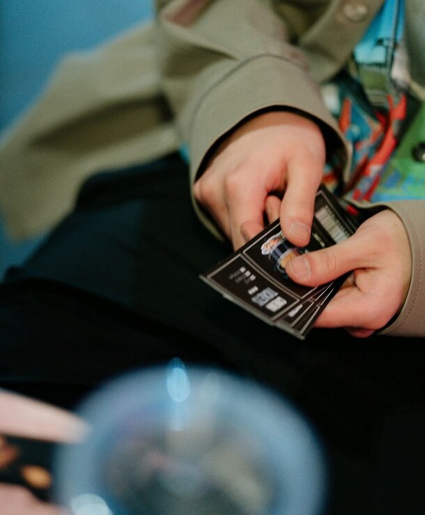 A person holding a card, displaying it towards the viewer with a focused expression.