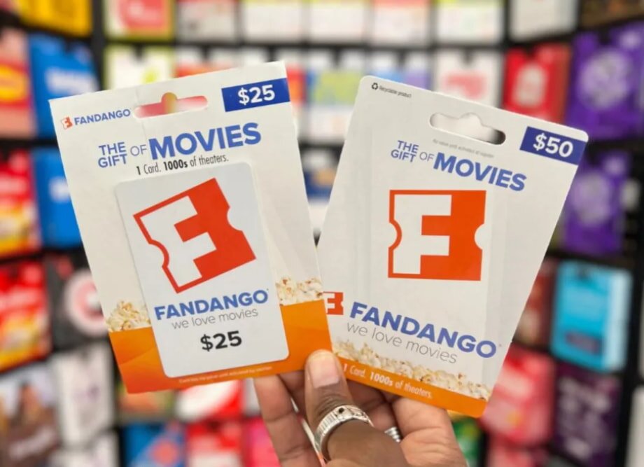 Two Fandango gift cards are held in hand against a blurred retail display. One has a $25 value, the other $50. Both feature Fandango's logo.