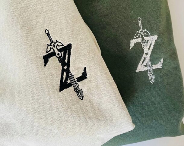 Two t-shirts adorned with the Legend of Zelda logo, arranged next to each other.