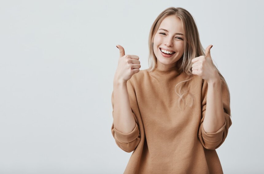 A woman smiles and gives a thumbs up, expressing positivity and approval.  