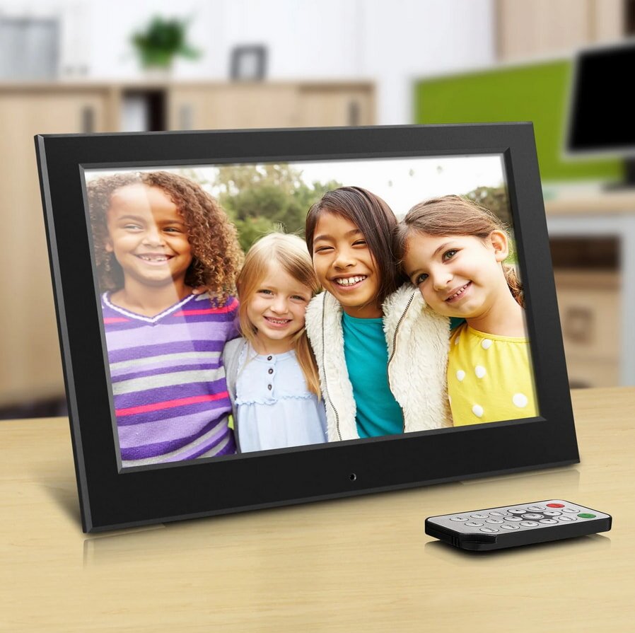 A picture frame positioned beside a remote control on a flat surface.