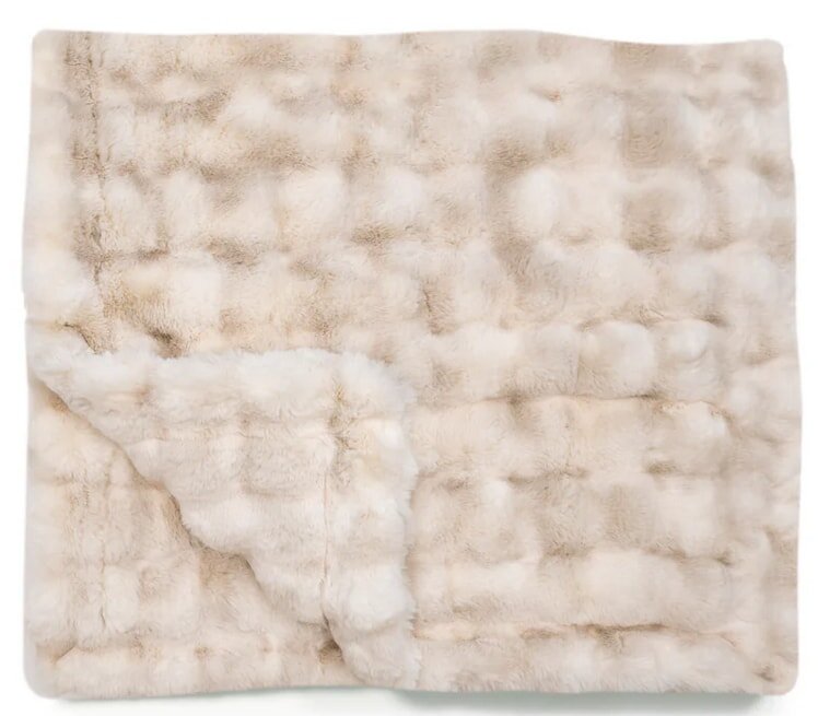 A soft, white fur blanket showcasing a fluffy texture, perfect for warmth and comfort.