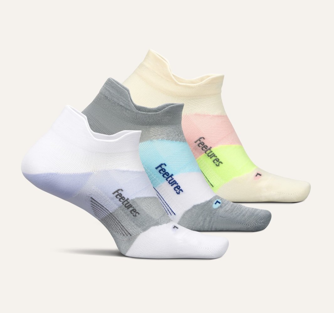 A display of three pairs of socks: one white, one pink, and one blue, showcasing their colors and patterns.