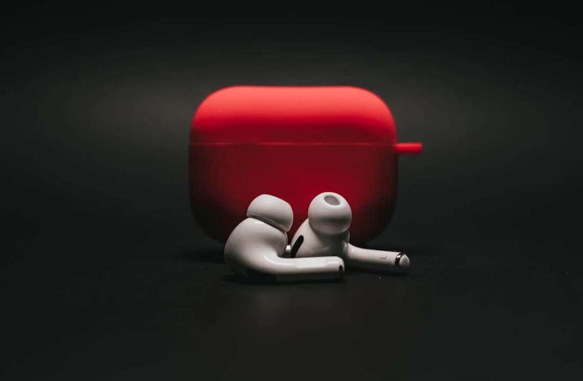 A white Apple AirPods case featuring a prominent red Apple logo on the front.