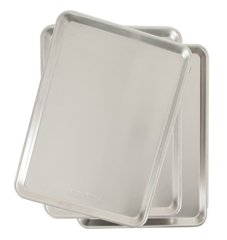 Three aluminum baking trays stacked neatly on top of each other, showcasing their shiny surfaces and rectangular shapes.