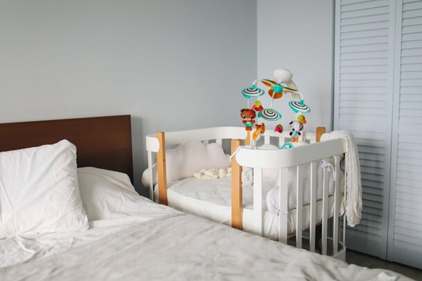 A serene bedroom featuring a baby crib adorned with white sheets.
