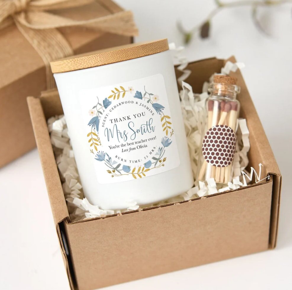 Gift box with a scented candle labeled “Thank You Mrs. Smith” and a small jar of matches. The candle has floral decorations, creating a warm, appreciative tone.