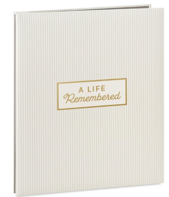 A cream-colored book with subtle vertical stripes. The cover has a gold-edged rectangle with the words "A Life Remembered," evoking a sense of nostalgia and reflection.