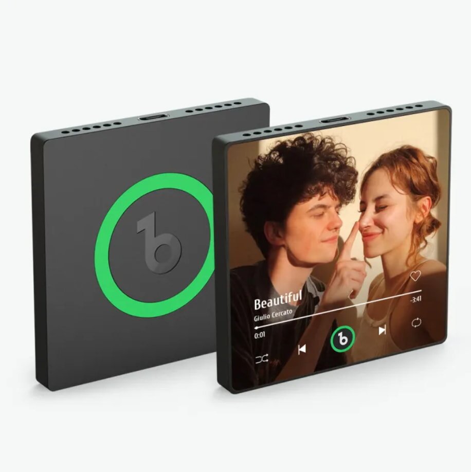 Compact touchscreen music player with a couple smiling on the display. The back shows a green circle with a "b" logo. The mood is joyful and intimate.