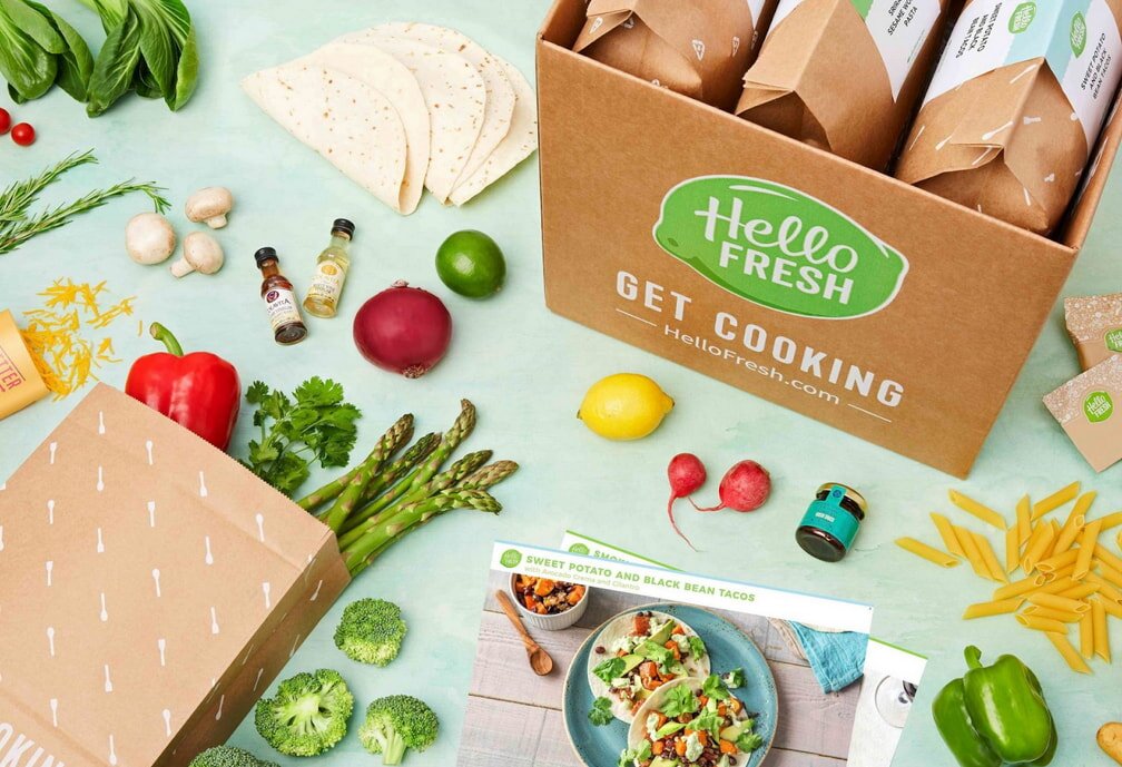 A skillet containing cooked potatoes topped with gooey cheese rests on a rustic table.