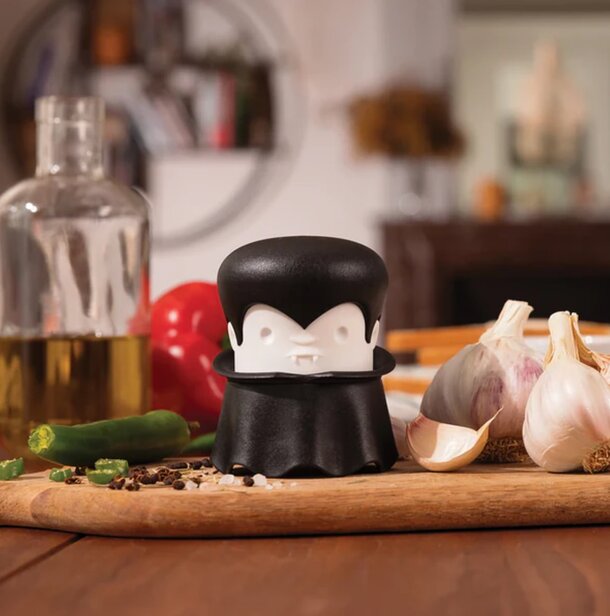 A pepper grinder topped with a black hat rests on a cutting board, adding a playful touch to the kitchen setting.