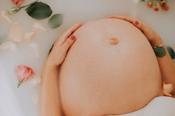 A pregnant woman relaxes in a bathtub adorned with colorful flowers, creating a serene and tranquil atmosphere.