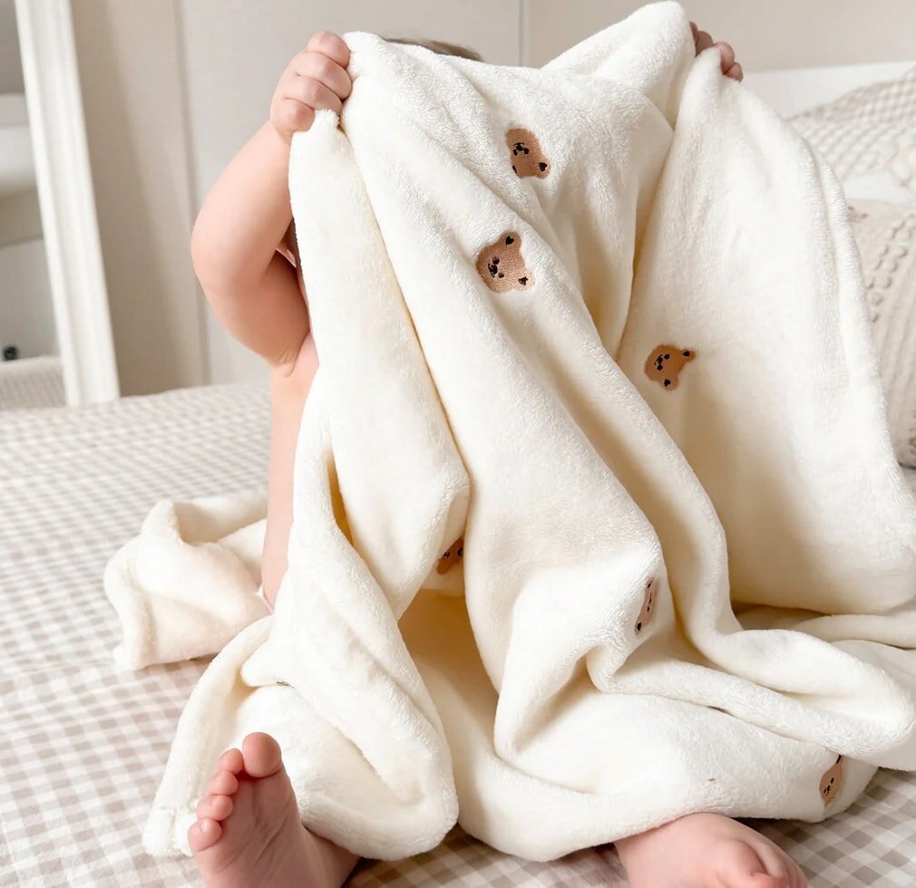 A baby swaddled in a soft white blanket, peacefully resting.