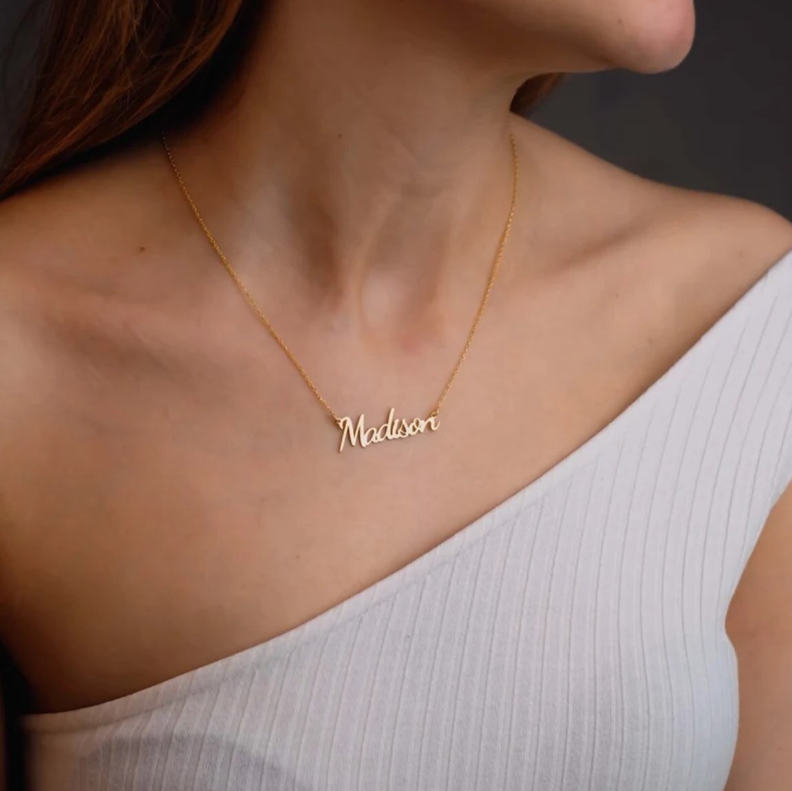 Close-up of a gold plated brass name necklace, highlighting its shiny finish and personalized charm.