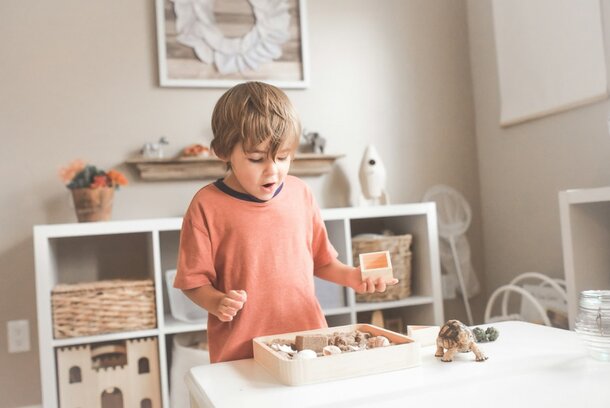 A young boy is engaged in play, stacking colorful wooden blocks in a bright and cheerful playroom.