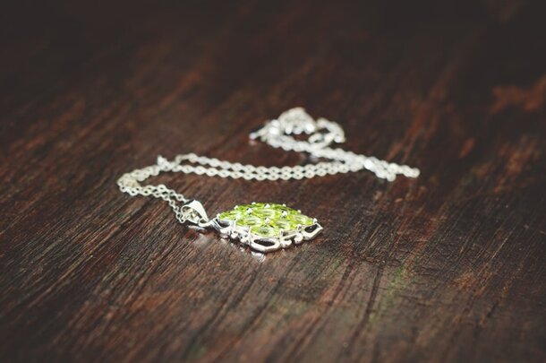 A green stone pendant hanging from a delicate silver chain, showcasing a simple yet elegant design.