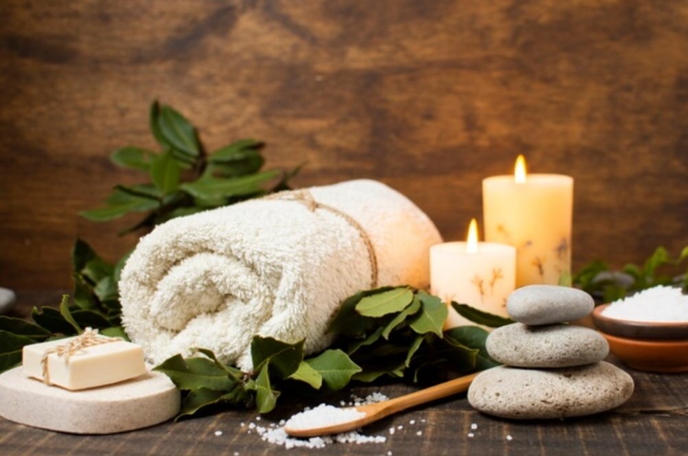 Spa items arranged on a wooden table, featuring candles and neatly folded towels for a relaxing atmosphere.
