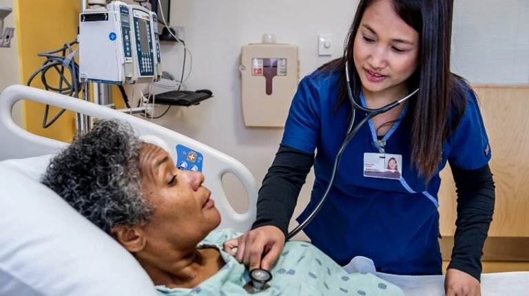 A nurse monitors the heart rate of an elderly woman during a medical check-up in a clinical setting.