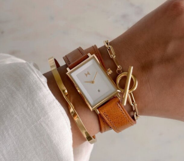 A woman wearing a gold watch on her wrist, complemented by a matching gold bracelet.