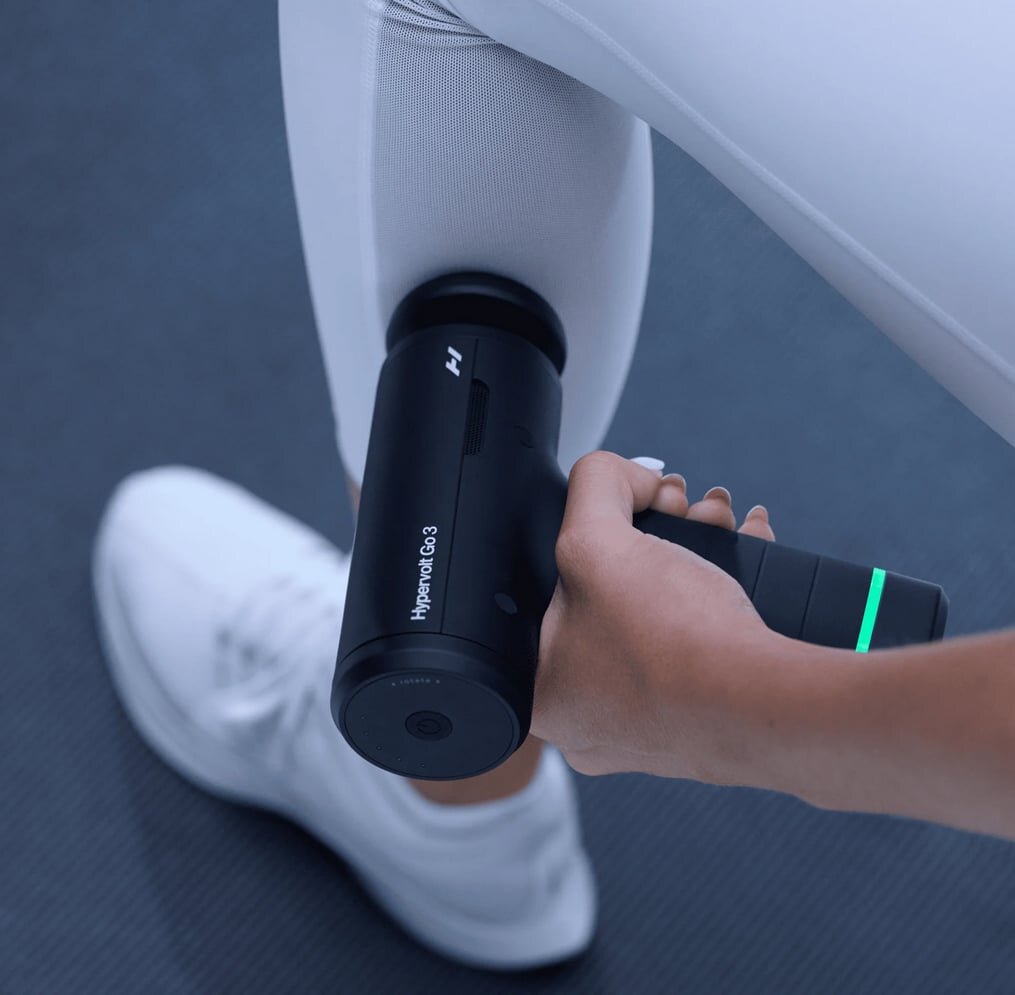 Hyperice Hypervolt Go 3 handheld massage gun next to its carry case.