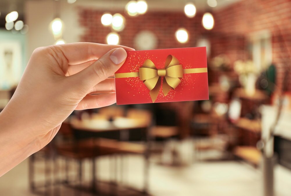 Hand holding red gift card with gold bow