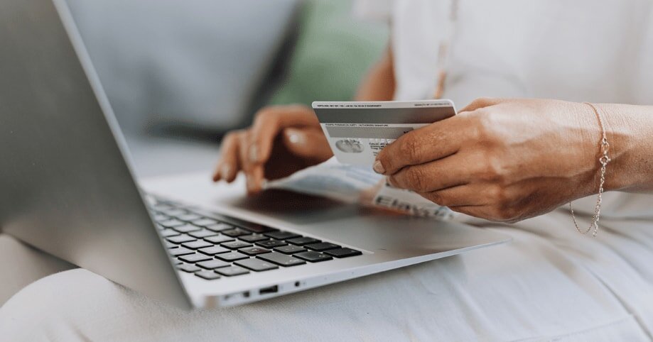 A woman sitting at a desk, using her laptop to complete an online payment for a product.