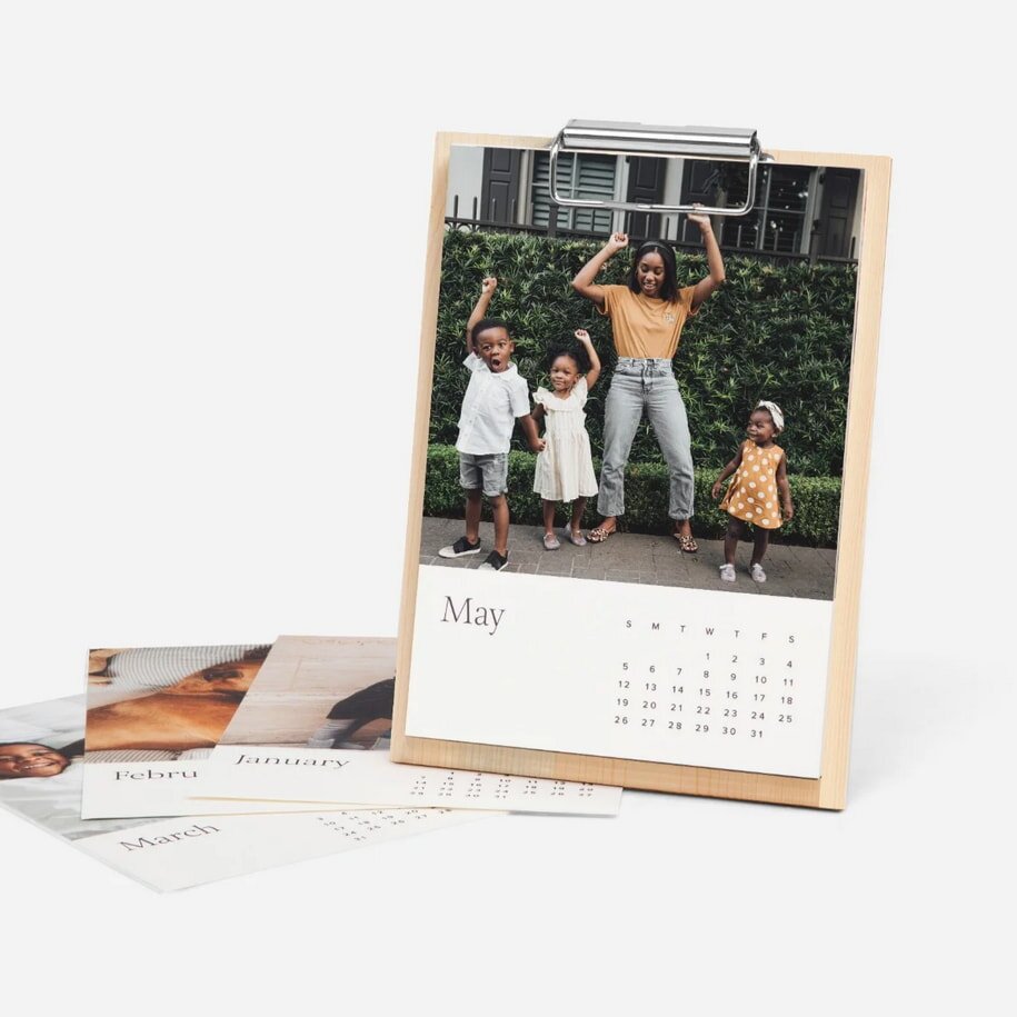 A wooden calendar featuring photos and a clip for displaying notes or reminders.