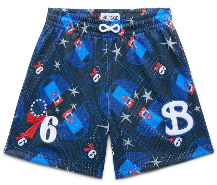 Dark blue basketball shorts with a drawstring waist, featuring a pattern of red and blue numbers, white stars, and various logos, conveying a sporty feel.