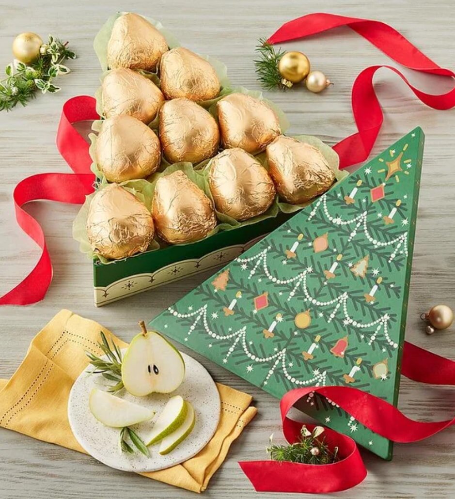 A decorated Christmas tree adorned with pears and a box of chocolates placed at its base.