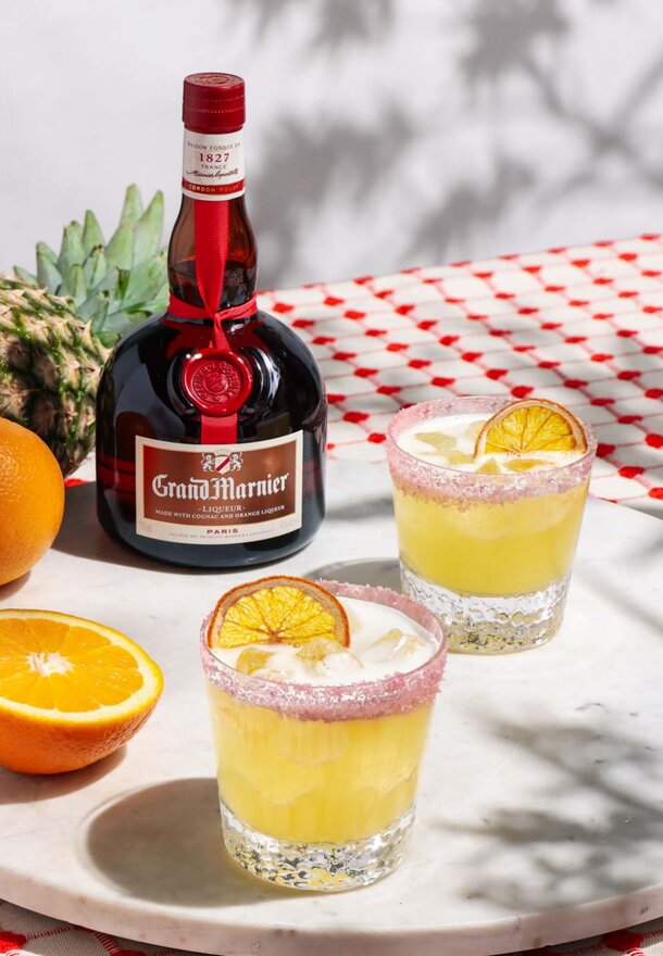 Two glasses of orange juice beside a bottle of champagne on a table, suggesting a celebratory setting.