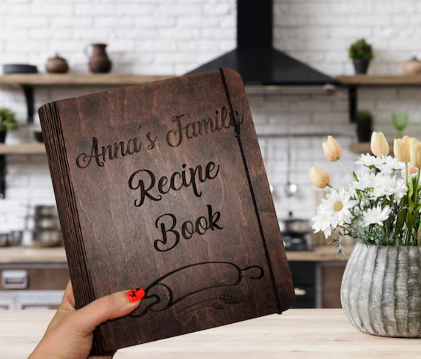 A personalized recipe book with a decorative cover, featuring handwritten notes and colorful tabs for easy navigation.