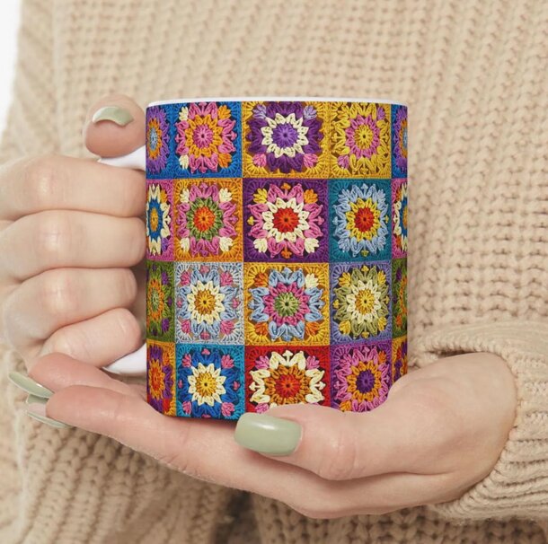A woman holds a vibrant mug adorned with a colorful flower pattern, smiling as she enjoys her drink.